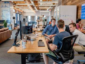 Photo of an office with 3 team members meeting around a desk